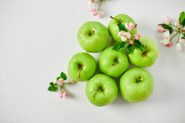 Düz elma çiçekleri ve olgun yeşil elmalar beyaz arka planda, meyveler ve çiçekler, sping konsepti. Üst görünüm