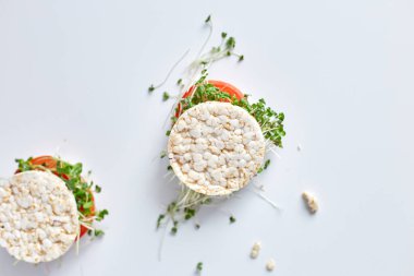 Üst Manzara Sağlıklı burger Çıtır pirinç ekmeği sebzeli domates ve beyaz arka planda mikro yeşiller, vegan beslenme, diyet yemekleri