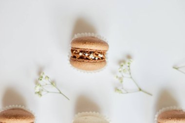 Farklı Fransız kurabiyelerinden oluşan üst manzara seti, beyaz arka planda çiçekli pasta makaronları, renkli badem kurabiyeleri, pastel rengi...