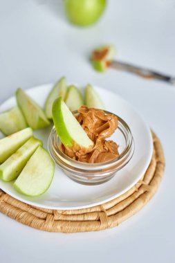 Yeşil dilimler beyaz arka planda fıstık ezmeli elmalar, sağlıklı atıştırmalıklar, beslenme yemekleri, diyet