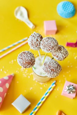 Festival birthday background with delicious homemade popcake coconut chocolate cake pops on a yellow background, festival desserts, tasty food