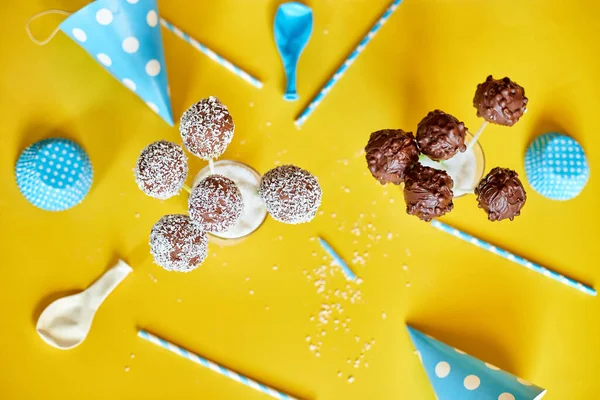 Festival birthday blue boy background with delicious homemade popcake coconut chocolate cake pops on a yellow background, festival desserts, tasty food