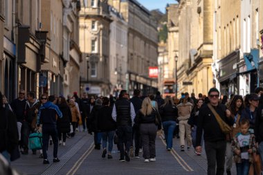 Bath, İngiltere, 15 Ekim 2023: İnsanlar Bath, İngiltere 'de şehrin alışveriş bölgesinde bir cadde boyunca yürüyorlar. Burası İngiltere 'nin ünlü tarihi şehri.