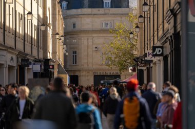Bath, İngiltere, 15 Ekim 2023: İnsanlar Bath, İngiltere 'de şehrin alışveriş bölgesinde bir cadde boyunca yürüyorlar. Burası İngiltere 'nin ünlü tarihi şehri.