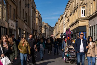 Bath, İngiltere, 15 Ekim 2023: İnsanlar Bath, İngiltere 'de şehrin alışveriş bölgesinde bir cadde boyunca yürüyorlar. Burası İngiltere 'nin ünlü tarihi şehri.