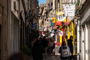 Bath, İngiltere, 15 Ekim 2023: İnsanlar Bath, İngiltere 'de şehrin alışveriş bölgesinde bir cadde boyunca yürüyorlar. Burası İngiltere 'nin ünlü tarihi şehri.