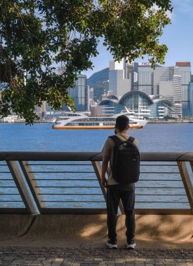 Tsim Sha Tsui, Hong Kong, Temmuz 2024: Turistler fotoğraf çekiyorlar ve Victoria Limanı boyunca uzanan ünlü Hong Kong adasının keyfini çıkarıyorlar 