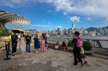 Tsim Sha Tsui, Hong Kong, Temmuz 2024: Turistler fotoğraf çekiyorlar ve Victoria Limanı boyunca uzanan ünlü Hong Kong adasının keyfini çıkarıyorlar 