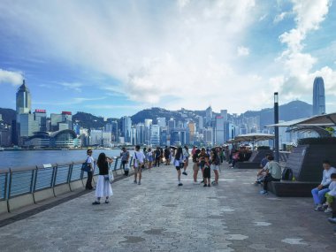 Tsim Sha Tsui, Hong Kong, Temmuz 2024: Turistler fotoğraf çekiyorlar ve Victoria Limanı boyunca uzanan ünlü Hong Kong adasının keyfini çıkarıyorlar 