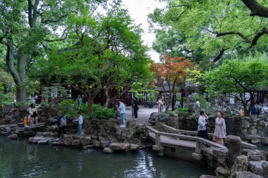 Şangay, Çin - Haziran 06, 2024: Serin Yu Garden, Şangay 'da yeşil ve canlı çiçeklerle çevrili bir taş köprü geçmektedir..