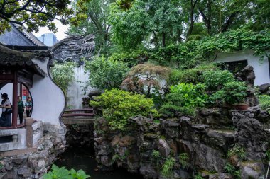 Şangay, Çin - Haziran 06, 2024: Yu Garden, Şangay 'da taş bir ejderha heykeli. Bahçede yemyeşil, kayalık yollar ve dingin bir gölet var..
