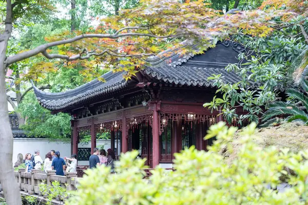 stock image Shanghai, China - June 06, 2024 : A traditional Chinese pavilion nestled amongst lush greenery in the Yu Garden, Shanghai, China. The structure's intricate details and red pillars stand out against the green foliage.