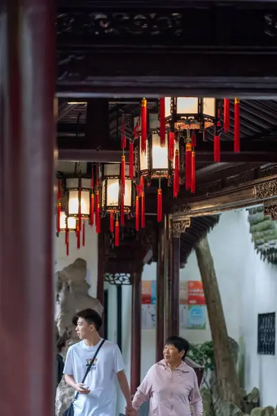 stock image Shanghai, China - June 06, 2024 : Two people walk through the Yu Garden in Shanghai, China, illuminated by traditional lanterns hanging from the ceiling.