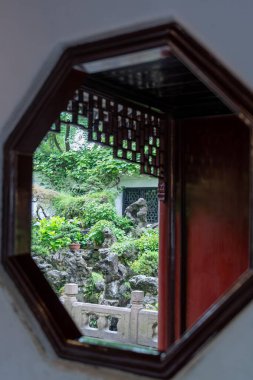 Şangay, Çin - Haziran 06, 2024: Şangay, Çin 'deki Yu Garden' da bahçenin karmaşık mimarisini ve yemyeşil bahçesini gösteren bir pencere manzarası.
