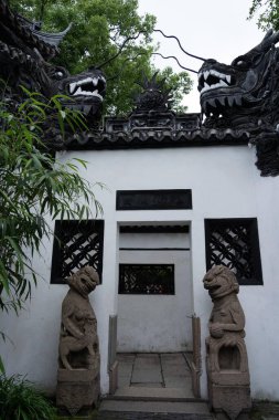 Şangay, Çin - Haziran 06, 2024: Taş aslan heykelleri Çin 'in Şangay kentindeki Yu Garden' ın girişini kuşattılar. Kapının tepesindeki karmaşık oyulmuş ejderha başları bu tarihi bölgenin geleneksel cazibesine katkı sağlıyor..