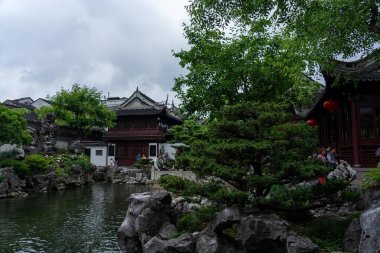 Şangay, Çin - Haziran 06, 2024: Yu Garden, Şangay 'da dingin bir gölet, geleneksel mimari, yemyeşil ve büyük kaya oluşumları ile çevrili..