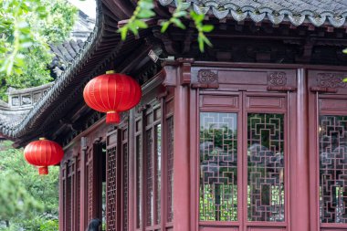 Şangay, Çin - Haziran 06, 2024: Bir kırmızı fener karmaşık kafes pencereli geleneksel bir Çin binasının önünde asılı duruyor. Yapı Çin, Şangay 'daki Yu Garden' ın bir parçası..