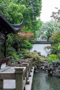 Şangay, Çin - Haziran 06, 2024: Yu Garden, Çin 'de sakin bir gölete bakan taş köprü. Yeşillik ve geleneksel mimari huzurlu bir atmosfer yaratır..