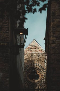 Cambridge, İngiltere 'de iki taş bina arasında yuvarlak pencereli bir tuğla bina bulunuyor. Bir sokak lambası sahneyi aydınlatıyor.