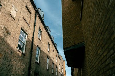 Cambridge, İngiltere 'de dar bir sokak, her iki tarafında yüksek tuğlalı binalar var. Binaların pencereleri ve yan taraflarında bir oluk var..