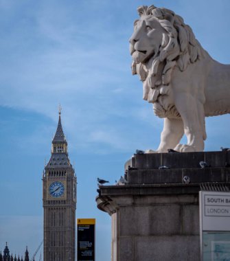 Londra, İngiltere - 09 Ekim 2023: Big Ben manzarası ve İngiltere 'de bir aslan heykeli. Gökyüzü birkaç bulutla mavidir.