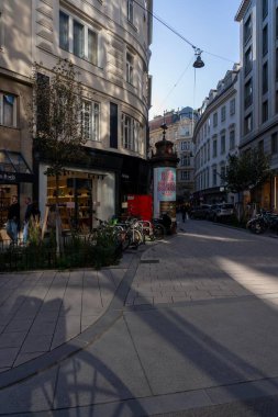 Wien, Avusturya - 28 Ekim 2023: Viyana, Avusturya 'da kaldırımda uzun gölgeler bırakan bisikletli bir sokak. Cadde her iki taraftaki binalarla dolu..