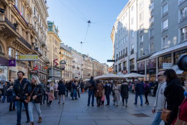 Wien, Avusturya - 28 Ekim 2023: Viyana, Avusturya 'da işlek bir sokak sahnesi. İnsanlar binalarla dolu geniş bir yaya caddesinde yürüyor..