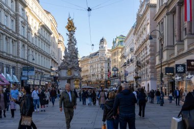 Wien, Avusturya - 28 Ekim 2023 Viyana, Avusturya 'da kalabalık bir cadde, süslü binalar, büyük bir heykel ve dükkanların önünden geçen bir kalabalık.