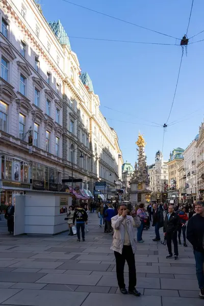 Wien, Avusturya - 28 Ekim 2023: Viyana, Avusturya 'da kalabalık bir cadde, tarihi binaların önünden geçen büyük bir kalabalık. Gökyüzü açık mavi ve güneş parlıyor..