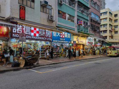 Hong Kong, Çin - 21 Temmuz 2024: Hong Kong, Çin 'de dükkan ve yürüyen insanlarla dolu bir cadde. Sokağa park edilmiş küçük bir otobüs var..