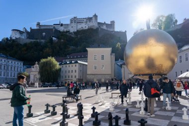 Salzburg, Avusturya - 01 Kasım 2023: Salzburg, Avusturya 'da büyük bir satranç tahtasıyla tarihi bir şatonun önünde dev bir altın küre duruyor..