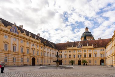 Melk, Avusturya - 25 Ekim 2023: Avusturya 'nın Melk kentinde kubbeli çatısı olan sarı bir binanın avlusunda bir çeşme bulunuyor.