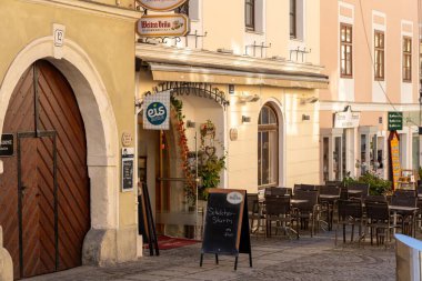 Melk, Avusturya - 25 Ekim 2023: Melk, Avusturya 'da kaldırımlı bir cadde, açık hava yemekleri için masa ve sandalyeler hazırlandı. Yerel biranın reklamını yapan bir tabela.