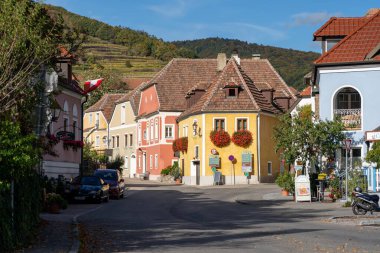 Vaçu, Avusturya - 26 Ekim 2023: Vaçu, Avusturya 'da renkli binalar, arka planda bir üzüm bağı yamacı ile çevrili tuhaf bir cadde.