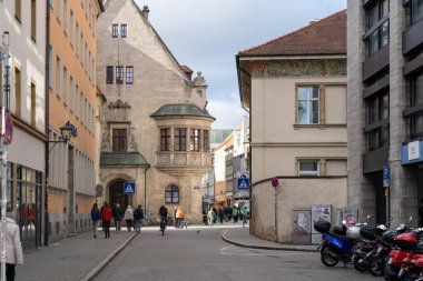 Regensburg, Almanya - 06 Kasım 2023: Regensburg, Almanya 'da eski binalarla dolu dar bir cadde. Yayalar ve bisikletçiler köşeyi dönüyor..