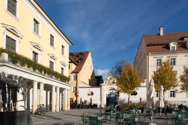 Regensburg, Almanya - 06 Kasım 2023: Regensburg, Almanya 'da tarihi binalar, bir heykel ve bir açık hava kafesi bulunan büyüleyici bir meydan.