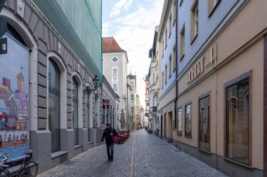 Regensburg, Almanya - 06 Kasım 2023: Regensburg, Almanya 'da renkli binalar ve yalnız yayalarla dolu dar, kaldırımlı bir cadde.