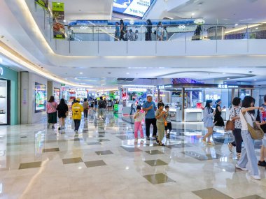 Shenzhen, Çin - 29 Temmuz 2024: Müşteriler Shenzhen, Çin 'deki parlak, modern bir alışveriş merkezinden geçiyor. Parlak zemin ışığı ve insanları yansıtıyor..