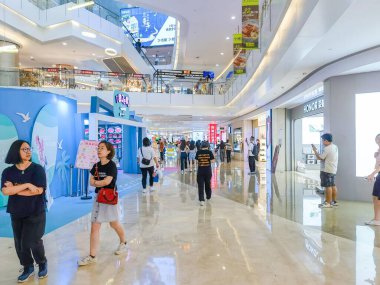 Shenzhen, Çin - 29 Temmuz 2024: Müşteriler Shenzhen, Çin 'deki parlak ışıklı ve modern bir alışveriş merkezinden geçiyor.