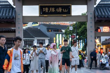 suzhou, China - June 10, 2024 : A bustling street in Suzhou, China, with a traditional gateway and people walking by. clipart