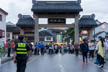 suzhou, China - June 10, 2024 : A bustling street in Suzhou, China, with people walking past a traditional archway. clipart