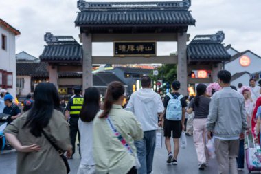 suzhou, China - June 10, 2024 : A crowd of people walking through a traditional Chinese gateway in Suzhou, China. clipart