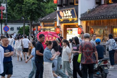 suzhou, China - June 10, 2024 : A bustling street in Suzhou, China, filled with people walking past shops and restaurants. clipart