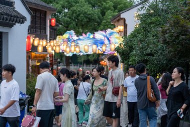 suzhou, China - June 10, 2024 : Crowds of people stroll through the streets of Suzhou, China, lit by colorful lanterns. clipart