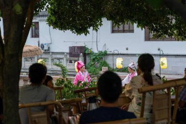 suzhou, China - June 10, 2024 : A woman in traditional Chinese clothing performs under a canopy of leaves in Suzhou, China. clipart