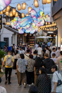 suzhou, China - June 10, 2024 : A bustling street in Suzhou, China, adorned with colorful lanterns and a crowd of people enjoying the evening atmosphere. clipart