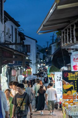 Suzhou, Çin - 10 Haziran 2024: Çin 'in Suzhou şehrinde insanların alışveriş yaptığı ve satıcıların mallarını sattığı hareketli bir sokak pazarı.