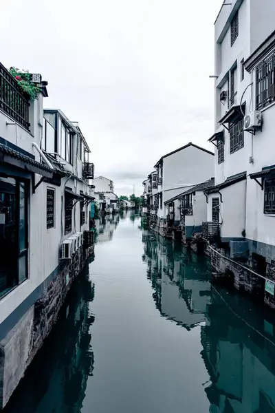 stock image suzhou, China - June 10, 2024 : A narrow canal in Suzhou, China, lined with white buildings reflecting in the still water.