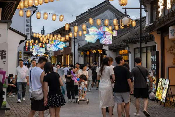 stock image suzhou, China - June 10, 2024 : A bustling street in Suzhou, China, adorned with traditional lanterns and colorful decorations.  People stroll along the cobblestone path, enjoying the festive atmosphere.