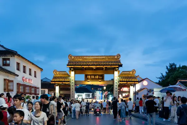 stock image suzhou, China - June 10, 2024 : A traditional Chinese gateway in Suzhou, China, illuminated at dusk with people walking through.